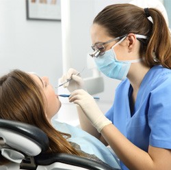 dentist looking in patient’s mouth 