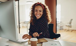 Woman smiling while sitting at desk in office