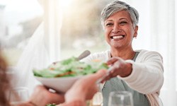 Woman smiling while grabbing bowl of salad