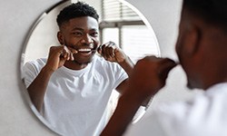 Man smiling while flossing his teeth