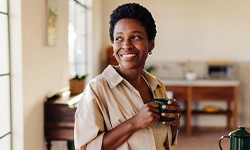Woman smiling while enjoying cup of tea at home