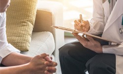 doctor holding a clipboard and sitting down with a patient