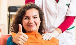 Smiling woman in dental chair giving thumbs up