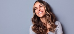 Curly haired woman smiling with a dental crown in Greenfield