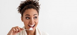 Woman in white robe brushing her teeth