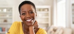 Woman in yellow shirt smiling while relaxing at home