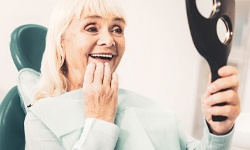 Woman smiling after getting implant dentures