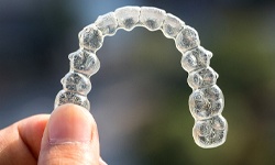 A person holding an Invisalign aligner