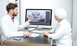 A dentist shows an older female patient her dental x-rays to explain why she needs a metal-free restoration in Greenfield