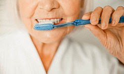 Woman brushing teeth to prevent dental emergencies in Greenfield