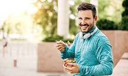 Man smiling while eating fruit bowl outside