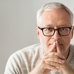 An older man covering his mouth.