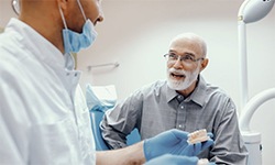 An older man speaking to a dentist.