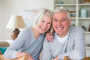 elderly couple in gray sweaters smiling