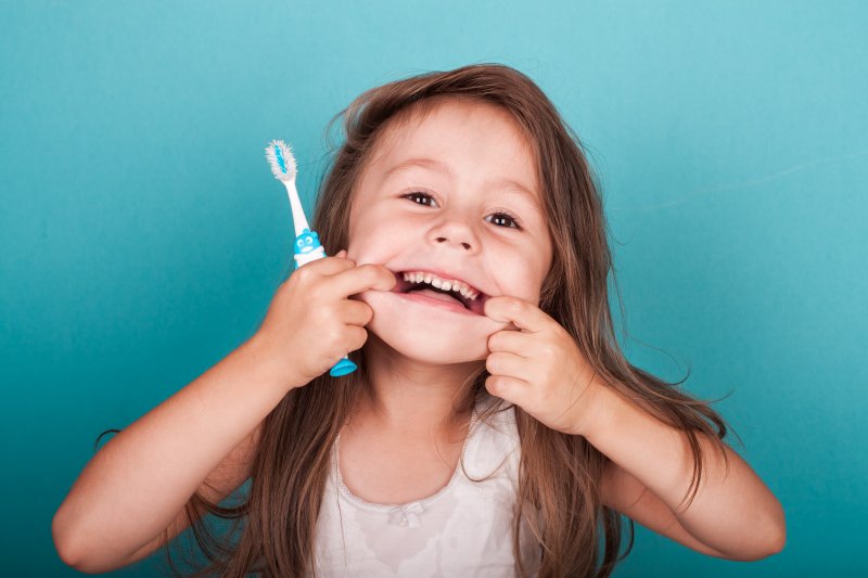 Little girl holding a toothbrush and making a funny face