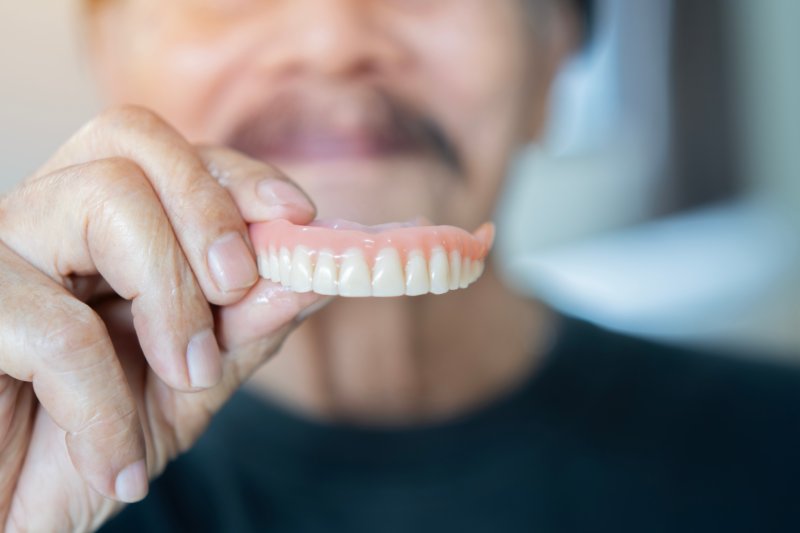 Patient holding up their old dentures