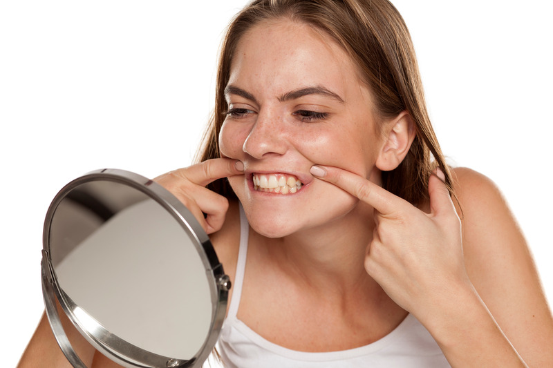 Patient checking their teeth in the mirror thinking about cosmetic dentistry