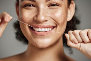 Closeup of a smiling patient flossing